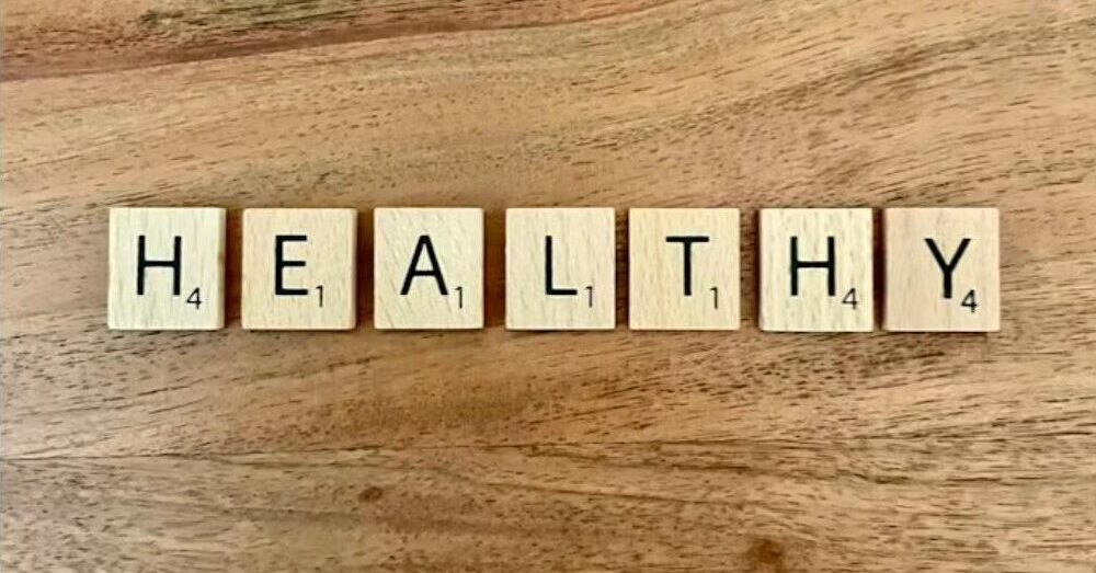 HEALTHY scrabble tiles on wooden table representing self-care and wellbeing
