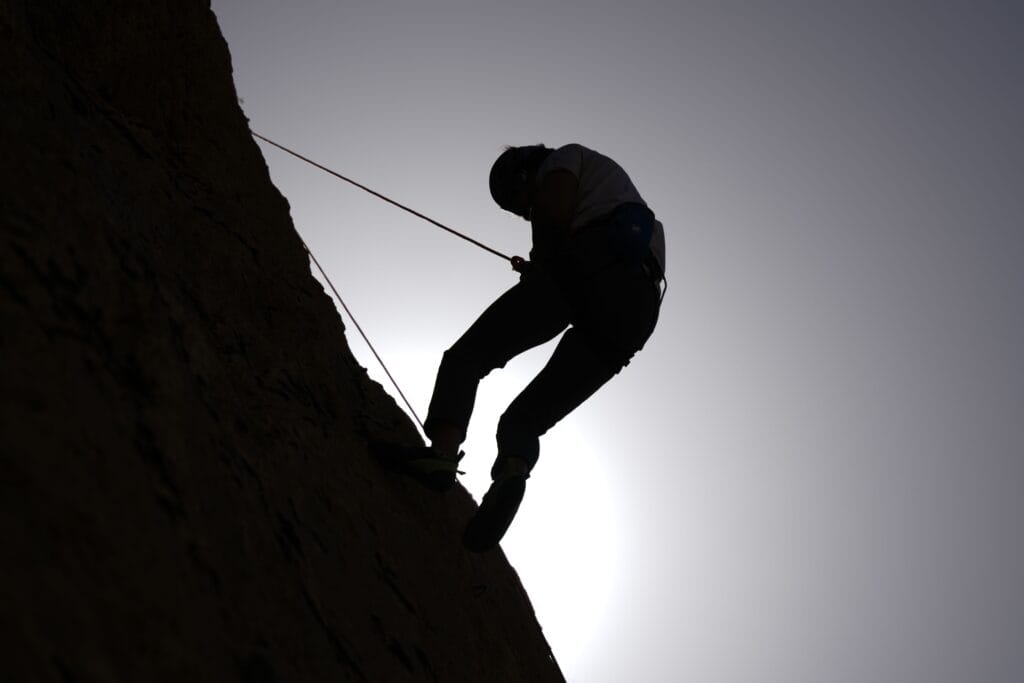 Person climbing rocky cliff face symbolizing mental toughness and determination