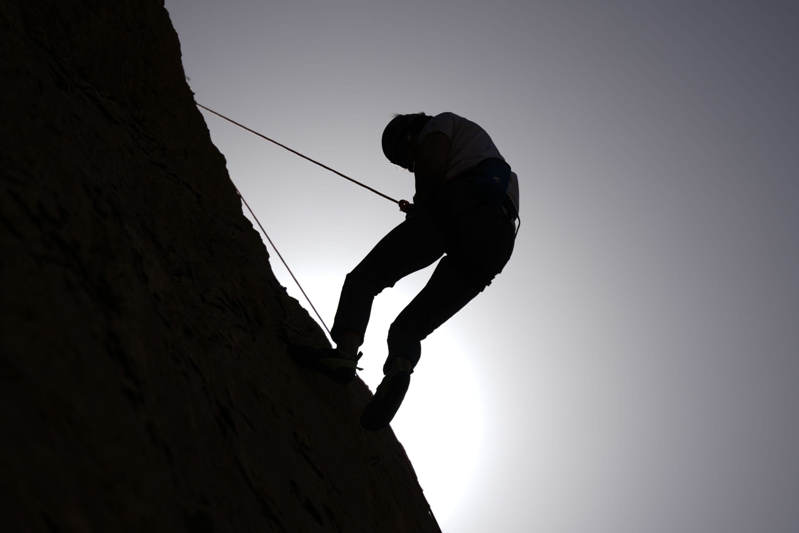 Person climbing rocky cliff face symbolizing mental toughness and determination