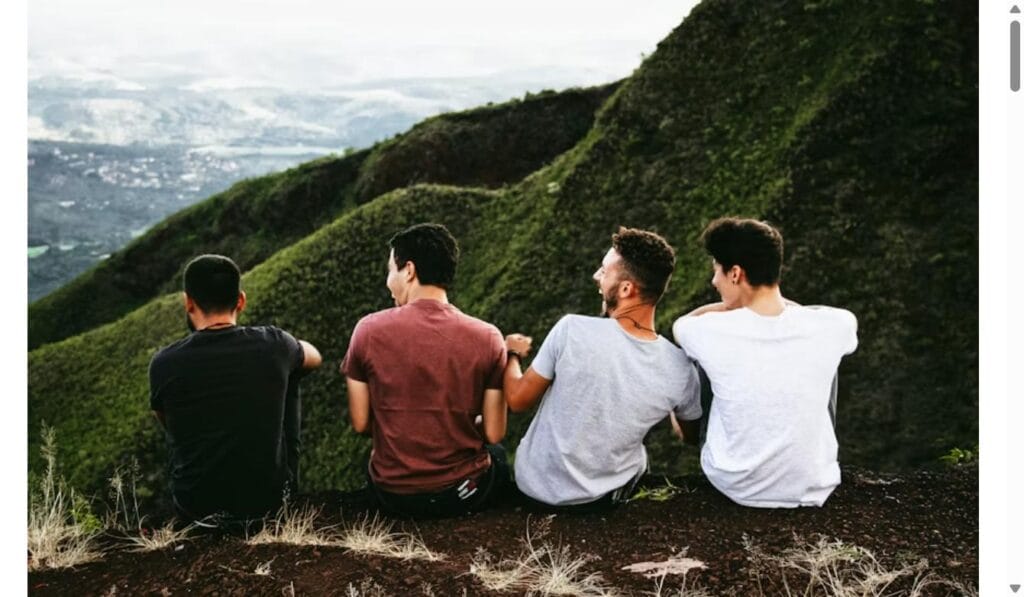 Four male friends sitting together on a mountain trail, reconnecting outdoors