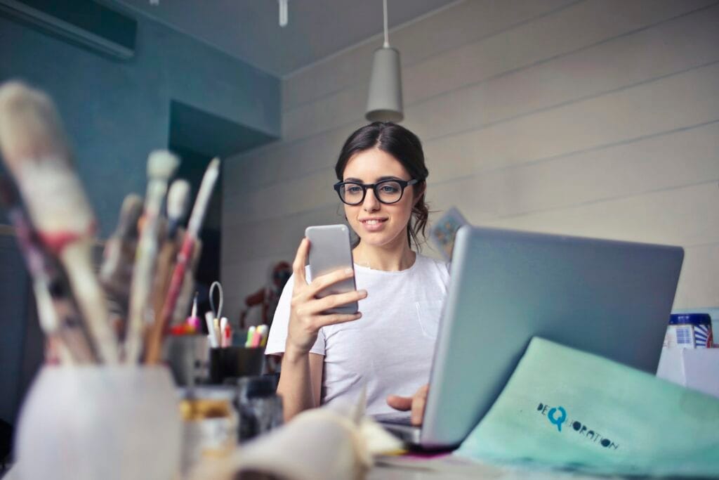Woman checking her phone at a desk while waiting for a reply