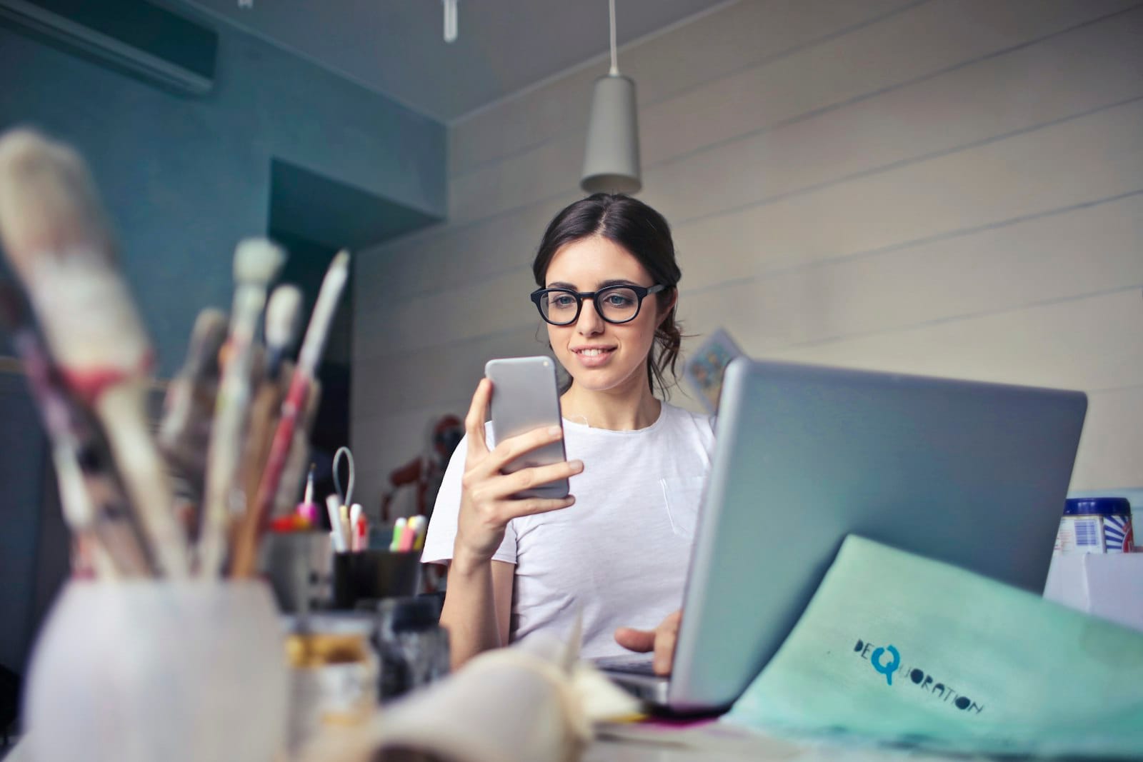 Woman checking her phone at a desk while waiting for a reply