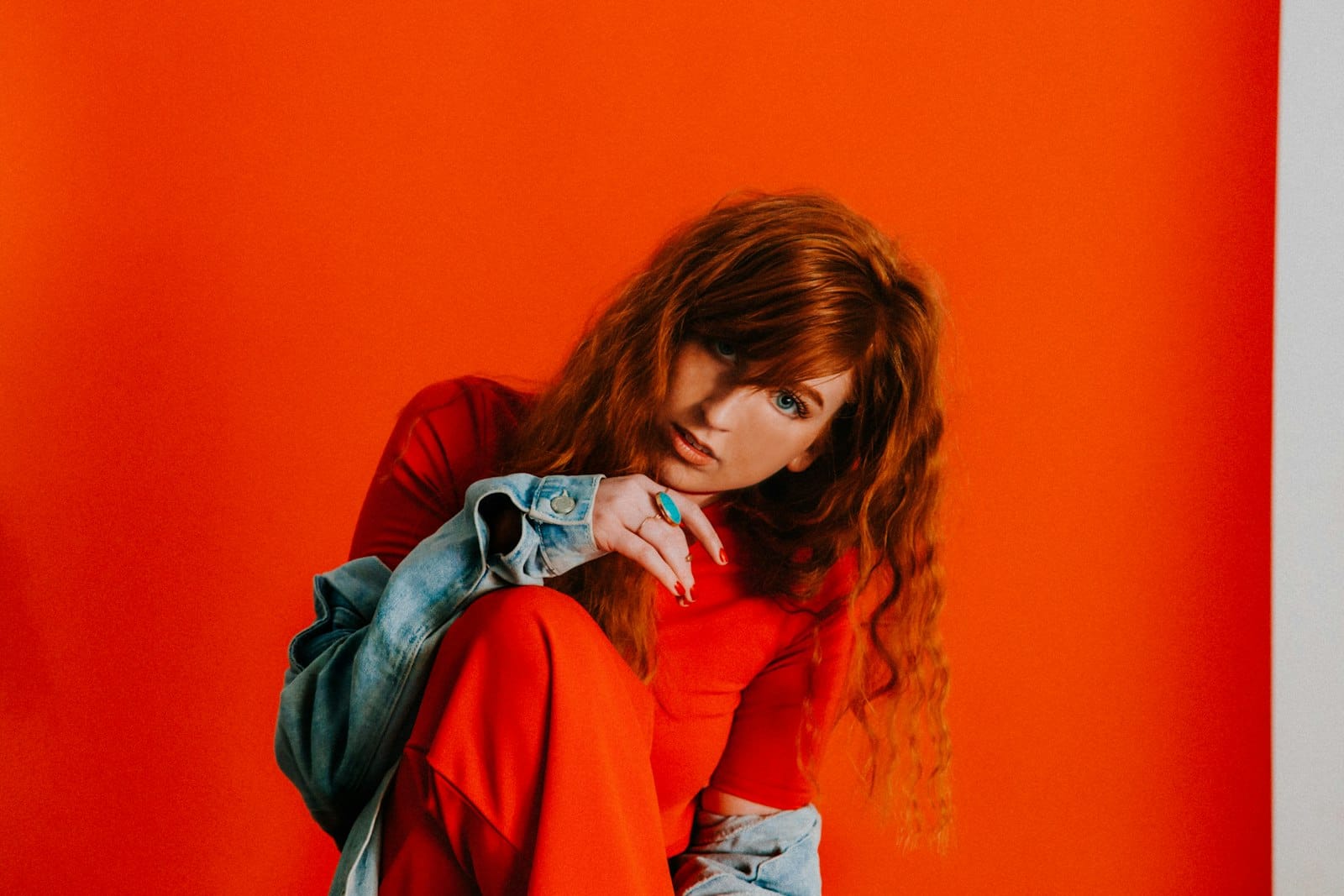 Woman with hair falling over her face against a red background, symbolising emotional withdrawal